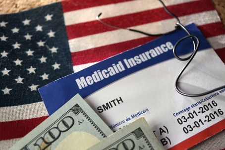 Medicaid insurance card with money on an american flag