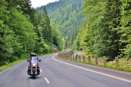 Motorcycle riding alone on wooded rural highway
