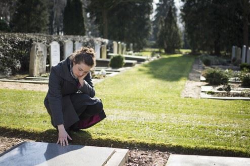 young woman visiting grave site of loved one